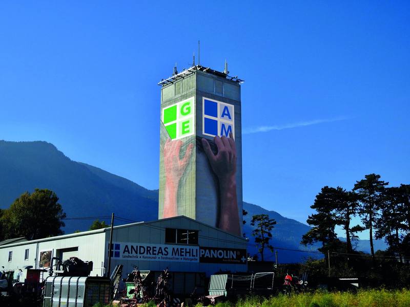 Der Mühleturm an der Rheinmühle mit dem Wandbild und den Firmenzeichen von GRegio und Andreas Mehli, davor die Halle