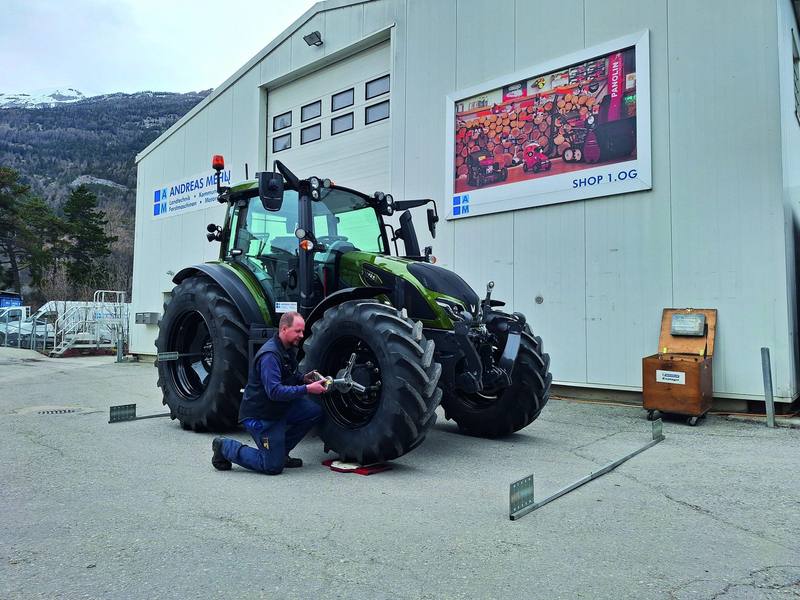 Mechaniker misst mit einem Lasergerät die Spur eines Valtra-Traktors vor der Werkstatt in Chur